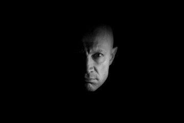 The male face is half darkened, black and white photo. Concept: night ghost. Mystical male portrait.