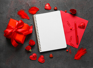 Romantic composition with empty notebook, gift and envelope on dark background