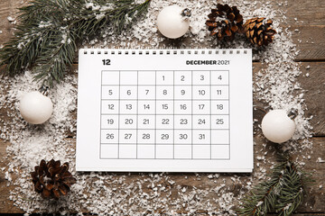 Calendar with date of winter solstice and decorations on wooden background
