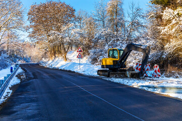 Excavator works in winter to repair the road. Excavator On Earthworks and Road Construction in the countryside in the Czech Republic. Road repair.