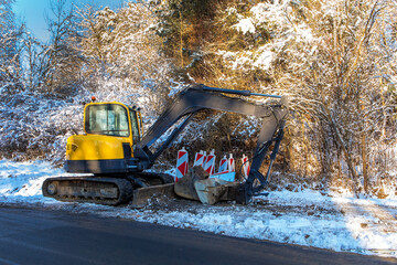 Excavator works in winter to repair the road. Excavator On Earthworks and Road Construction in the...