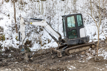 Excavator works in winter to repair the road. Excavator On Earthworks and Road Construction in the countryside in the Czech Republic. Road repair.