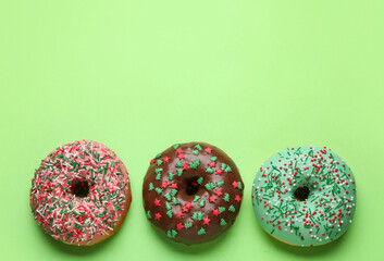 Tasty Christmas donuts on green background