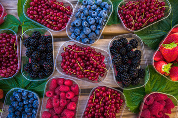 top view berries in trays over wooden table
