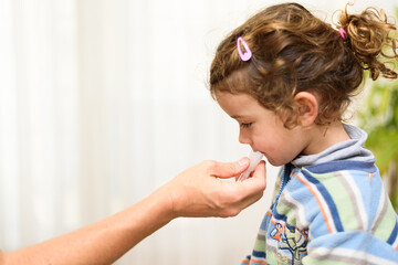 A three-year-old girl spits into a saliva test tube for covid19 antigens.