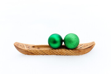 Wooden boat on snow with two green Christmas glittery balls on top