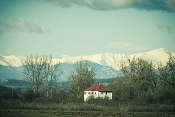 A beautiful white house. In the background hills, valleys and snow-capped mountains.