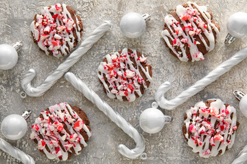 Tasty candy cane cookies and Christmas balls on grey background