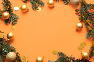 Frame made of Christmas balls and fir branches on orange background
