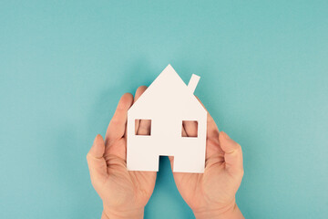 Holding a small paper house in the hands, planing to buy or rent a new home, real estate, owning property