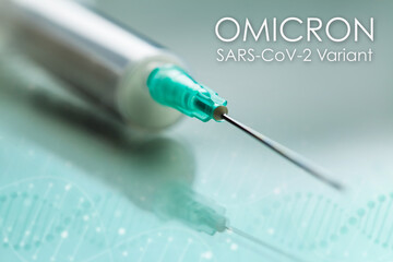 White syringe with green needle on reflective background with text OMICRON SARS-CoV-2