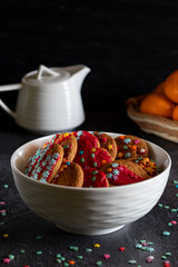 Christmas cookies, tangerines and a white teapot on a dark background