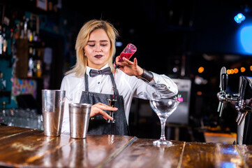 Girl barman makes a cocktail at the alehouse