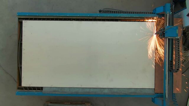 Laser cutting of a designed figure from metal by means of the programmable electric jigsaw machine. Automation in factories and industries. Sparks from metal cutting. 4k vide. View from above