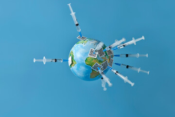 The planet earth is pricked with syringes on the needles of which QR codes are strung. Copy space.