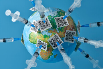 Planet earth close-up with lots of syringes and QR codes on a light blue background. Copy space.