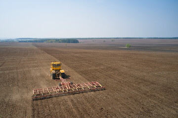 Pre-sowing preparation of the field. Harrowing the soil with a tractor. Shooting from a drone.