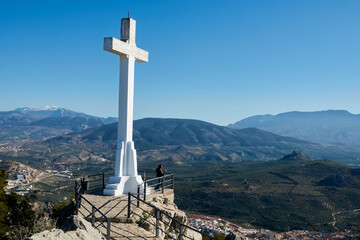 Large white stone cross on the hill of Santa Catalina in Ja&eacute;n (Spain) and its views over mountains of crops
