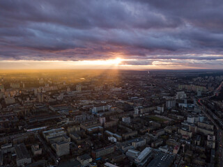 Sunset through the clouds over the city. Aerial drone view.