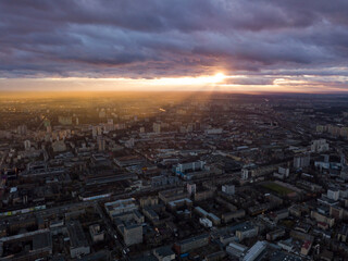 Sunset through the clouds over the city. Aerial drone view.
