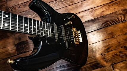 Black electric guitar on wooden background