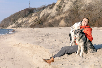 young happy woman hugging dogs on the beach