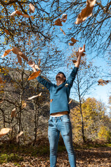 close up. young man plays with yellow leaves falling down. vertical composition