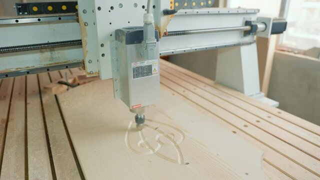 CNC machine cuts figures on a wooden blank close-up