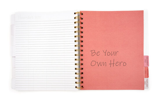 notebook with the inscription BE YOUR OWN HERO on white background