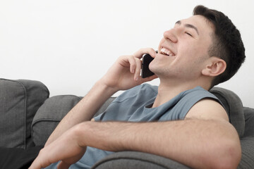 guy on sofa laughing while talking on phone