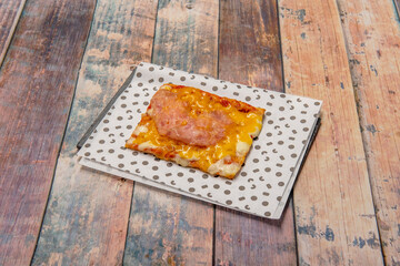 Rectangular slice of pizza with freshly baked cheddar bacon toppings