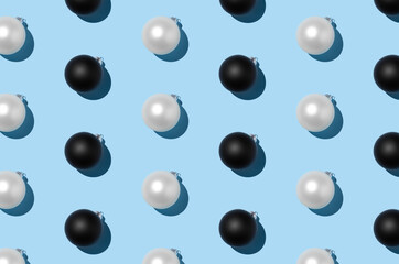 White and black Christmas balls pattern on a pastel blue background.