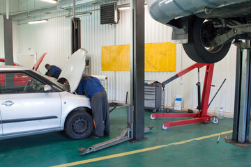 Mechanics repair cars in an auto repair shop