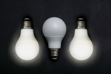 two luminous and one non-illuminating white bulb on black background