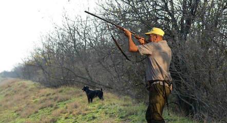 Hunter man in camouflage with a gun during the hunt in search of wild birds or game. Autumn hunting...
