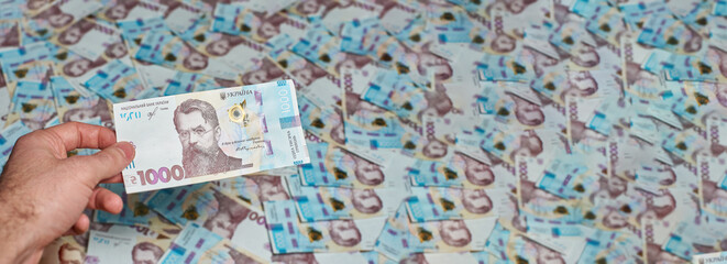 Naklejka premium Ukrainian money. Background of Ukrainian money. Banner of banknotes. The hand holds the Ukrainian 1000 hryvnia.