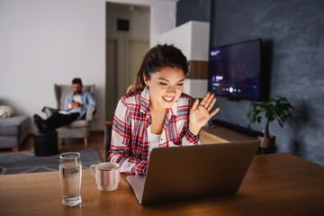 Smiling happy woman sitting at home during lockdown and having video call with her loved ones.