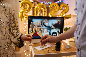 Naklejka na ściany i meble Celebrating Virtual Christmas New Year's Eve party 2022 at home during Covid-19 pandemic. Couple holding and toasting champagne glasses How to celebrate and decorate foiled balloons of 2022. 
