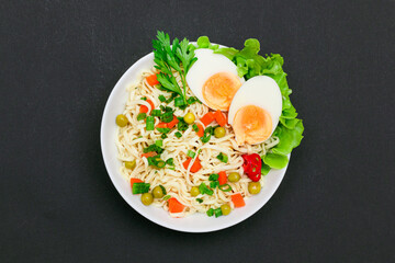 Beautiful Noodle Dish with Green Pea, Carrot, Eggs, Red Hot Pepper and Greens on Black Background. Instant Noodles with Vegetables