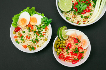Beautiful Noodle Dish with Green Pea, Carrot, Eggs, Red Hot Pepper and Greens on Black Background. Instant Noodles with Vegetables
