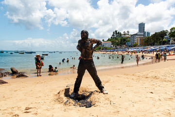 Man performs theatrical performance of Garlic and Oil. People on the beach watch his performance.