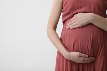 Fototapeta na wymiar Young pregnant woman on light background, closeup. Space for text