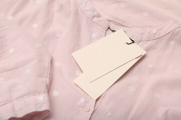 Blank white tags on light pink shirt with polka dot pattern. Space for text