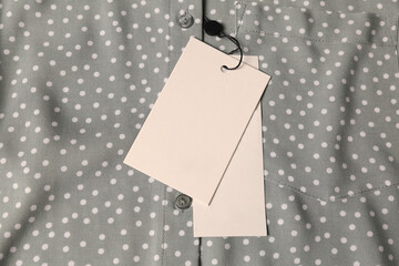 Blank white tags on grey shirt with polka dot pattern, top view. Space for text