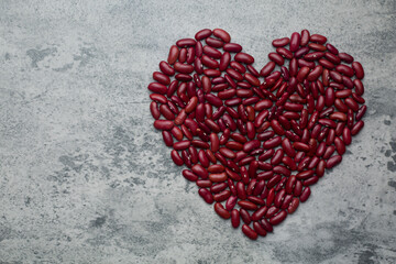 a pile grains red kidney beans heart shape on concrete background