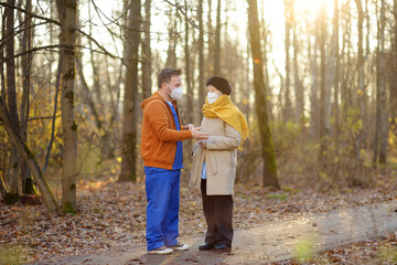 Fototapeta premium Nurse or volunteer looks after an elderly lady patient while walking in park. Caring for sick person. Boarding houses for the elderly. Nursing home. Professional nurses.