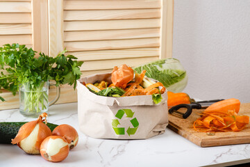 Sorted kitchen waste in paper eco bag on kitchen counter top. Compost-container. Sustainable life style. Vegetable and fruit peels, scraps from food preparation collected in trash-pack for recycling - 475777169