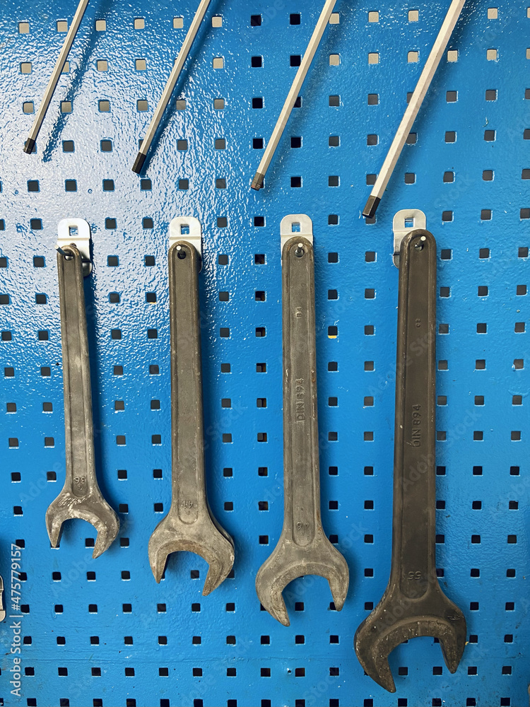 Poster Closeup of wrenches on a blue metal wall