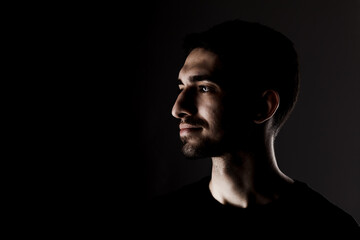Side lit contour portrait of young handsome male with short beard