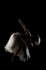 ballerina with a white dress and black top posing on black background. side lit silhouette. © Nikola Spasenoski